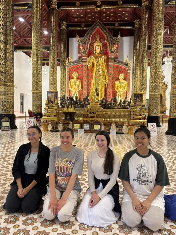 Four tourist women praying in temple in Thailand.