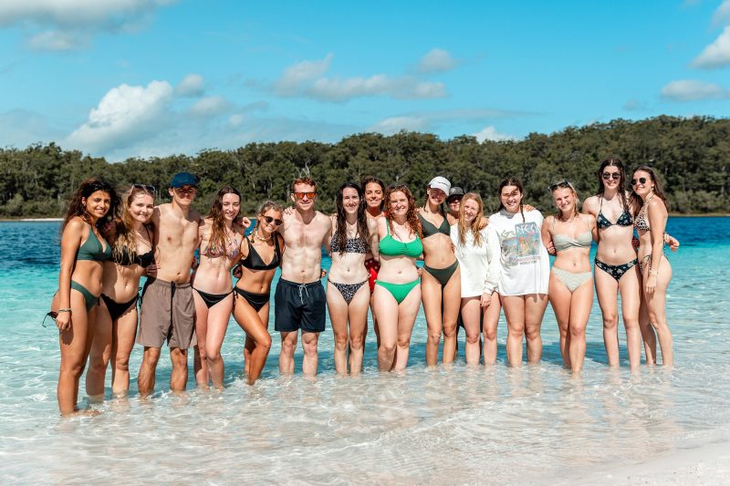 Group of young people in the sea smiling towards camera